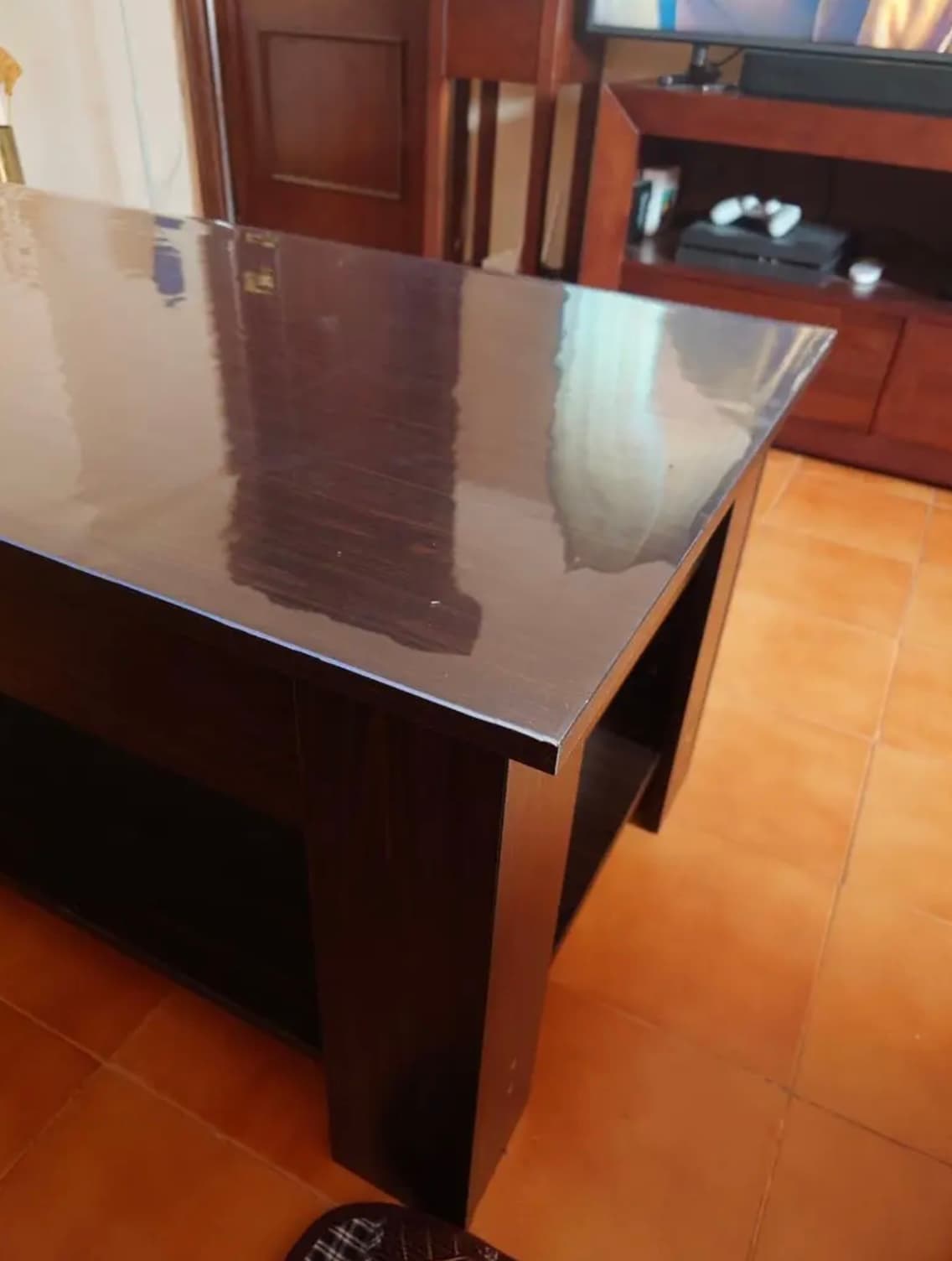 Ciemna konsola z wenge w salonie, blat pod przezroczystą matą, na podłodze terakota